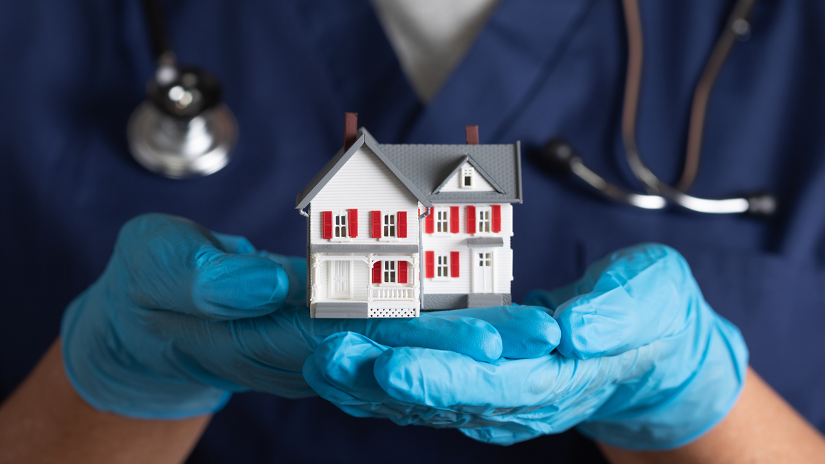 Medical work wearing gloves and holding toy house in hands